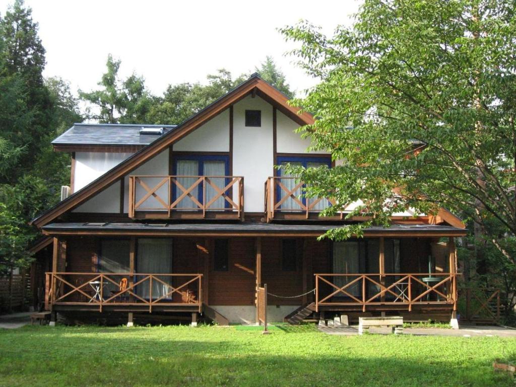 ein Haus mit einer umlaufenden Veranda und einem Balkon in der Unterkunft Hakuba-ism in Hakuba