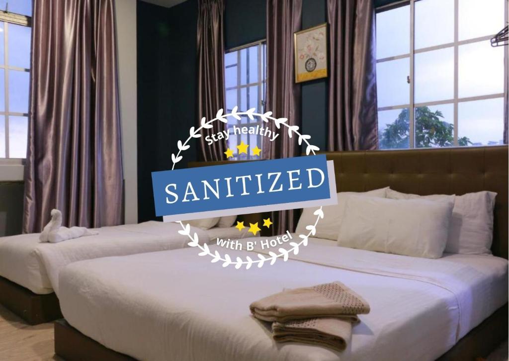 Dos camas con un letrero que dice "santitizado" en The b'Hotel en Kajang