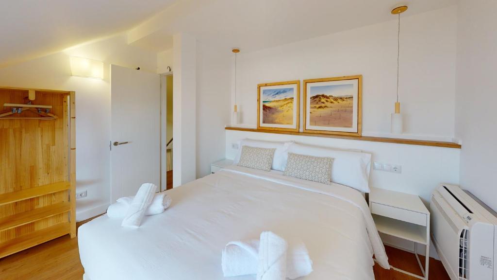 a white bedroom with a large white bed with two pillows at Apartamentos La Casa El Palo in El Rompido