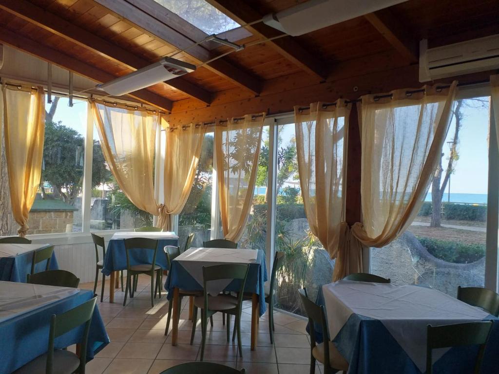 een eetkamer met tafels, stoelen en ramen bij Room in BB - Quadruple room in Pineto - A few meters from the sea in Pineto