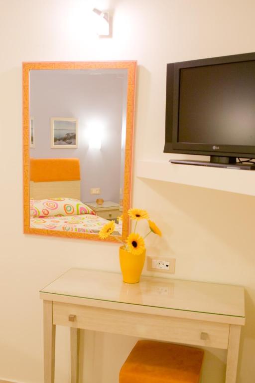 a room with a table with a tv and a mirror at Amaryllis Hotel Apartments in Tolo