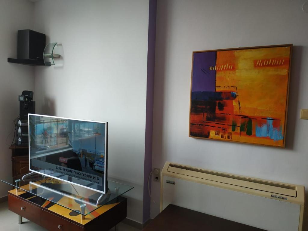a glass display cabinet with a laptop on it next to a painting at Marshov Rehovot - Apartment in center of Rehovot near shopping mall and Weizmann Institute in Rechovot