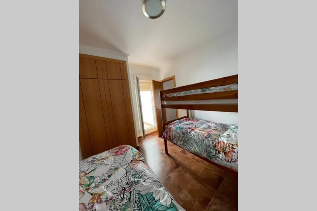 a bedroom with two beds and a bunk bed at Casa adosada con porche, piscina y pista de pádel, junto al campo de golf in El Portil