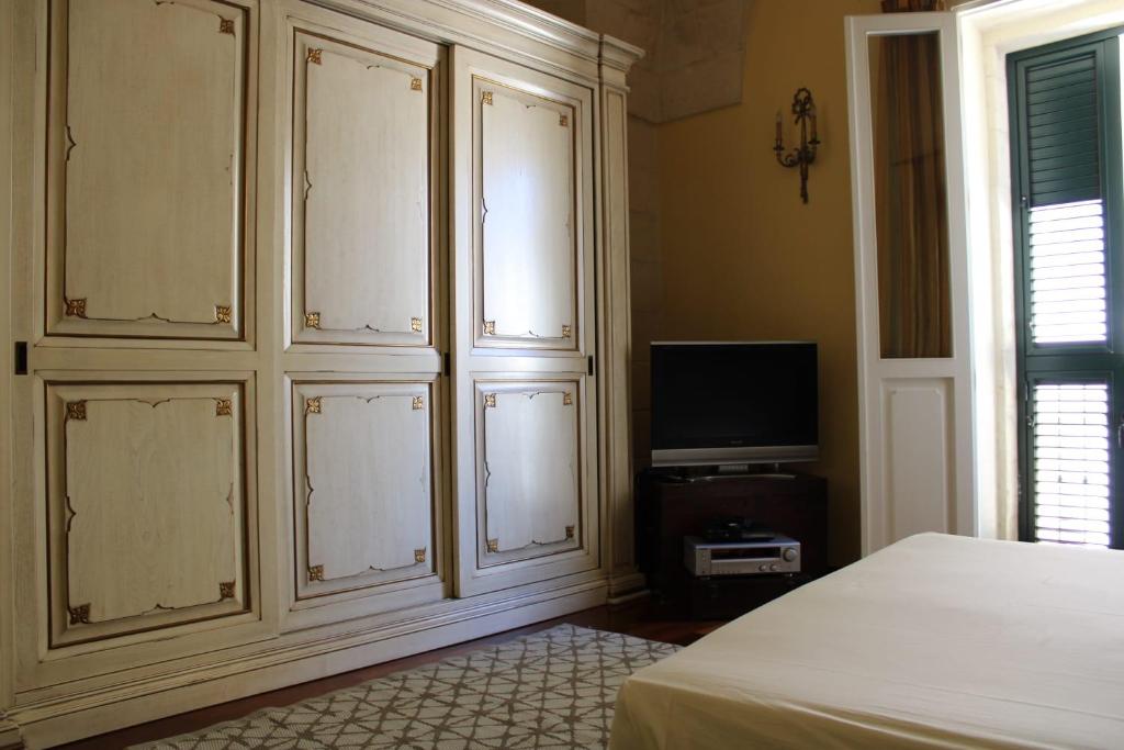 レッチェにあるGiravolte Suiteの白い大きなキャビネットとテレビ付きのベッドルーム1室