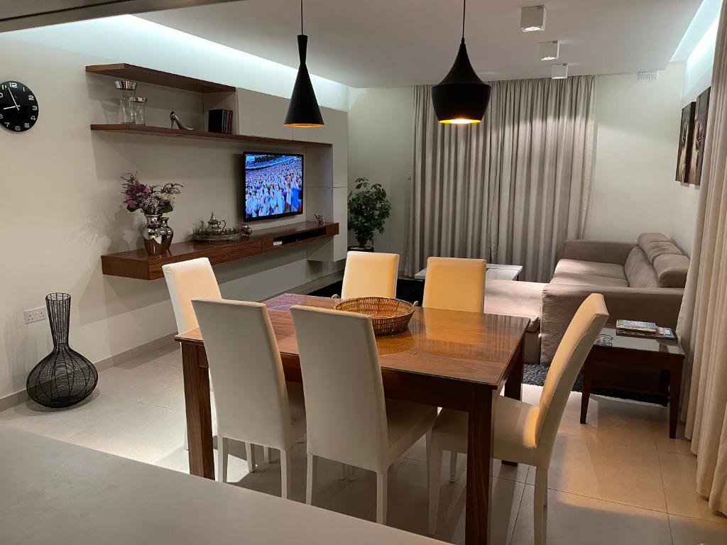 a dining room with a table and chairs and a couch at Deluxe Apartment with pool in the heart of St Pauls Bay in St. Paul's Bay