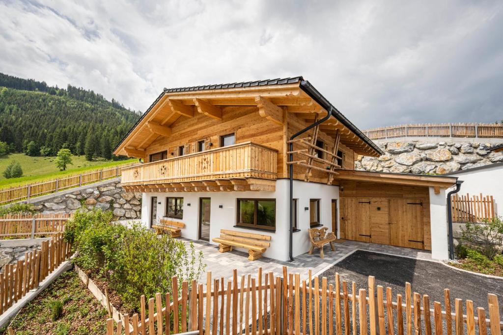 a log home with a deck and a wooden fence at Almdorf Auszeit Fageralm in Forstau
