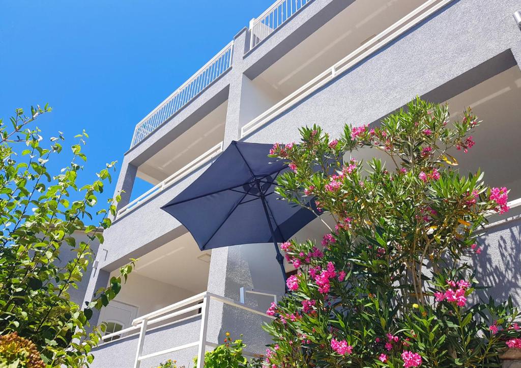 a blue umbrella in front of a building with flowers at Villa Skalinada with sea view in Brela