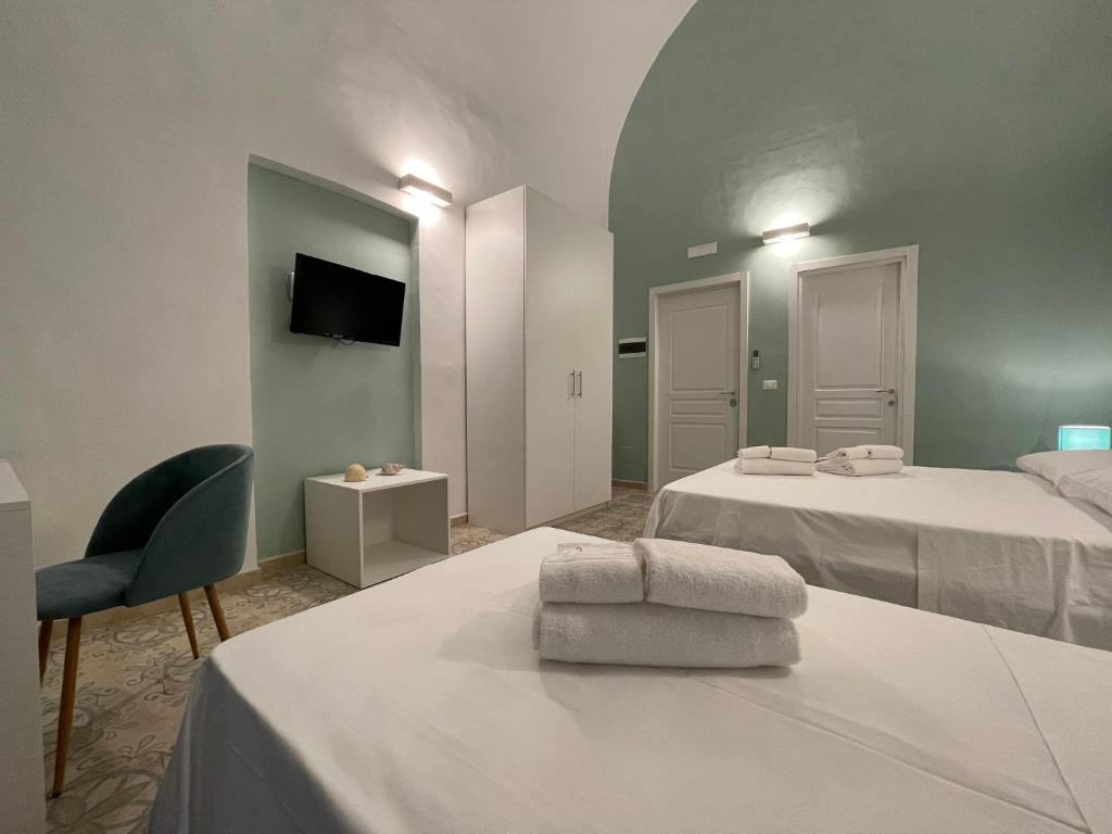 Cette chambre comprend deux lits, une chaise et une télévision. dans l'établissement Donna Grazia Relais, à Gallipoli