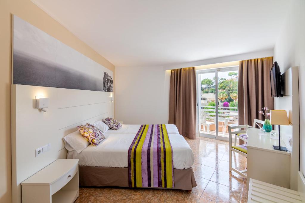 a hotel room with a bed and a balcony at Hotel Venecia Paguera in Paguera