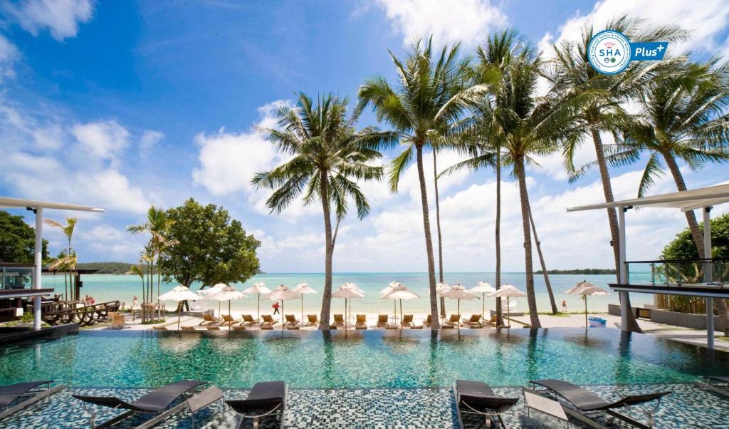 uma piscina com cadeiras e palmeiras e o oceano em Sareeraya Villas & Suites em Chaweng