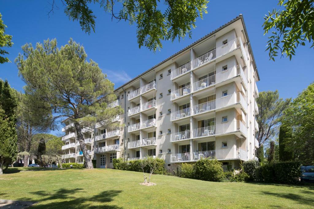 an apartment building with a lawn in front of it at Résidences LES HAUTES PLAINES in Gréoux-les-Bains