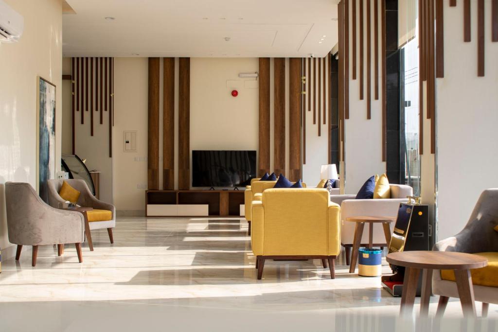 un vestíbulo con mesas y sillas amarillas en The Palace Hotel Suites - Al Badea, en Abha