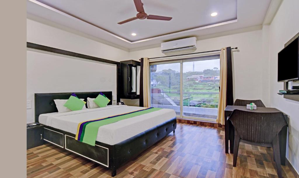 a bedroom with a bed and a desk and a window at Treebo Trend Paradise Inn Panchgani in Mahabaleshwar