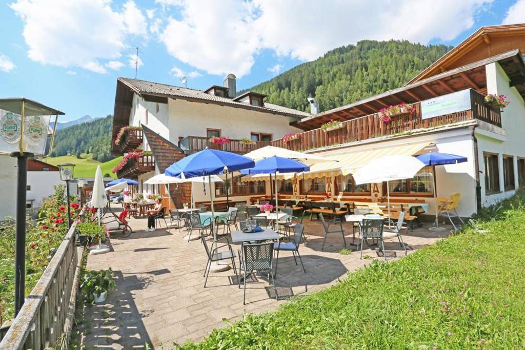 a patio with tables and umbrellas in front of a building at Gasthof Albergo Neuwirt in Val di Vizze