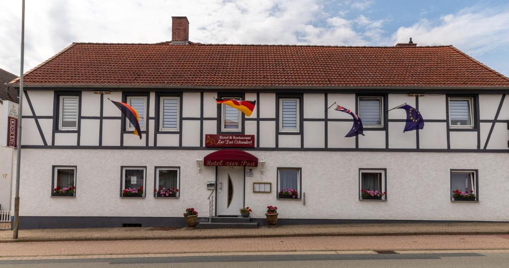 a white building with flags in front of it at Hotel zur Post Ochsendorf in Königslutter am Elm