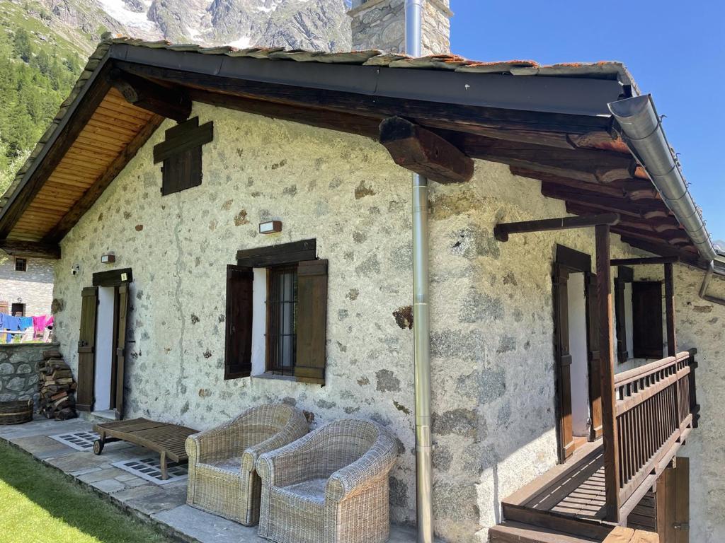 Cette maison en pierre dispose d'une terrasse couverte avec 2 chaises. dans l'établissement L'Atelier du Temps - Baita Grandes Jorasses, à Montita