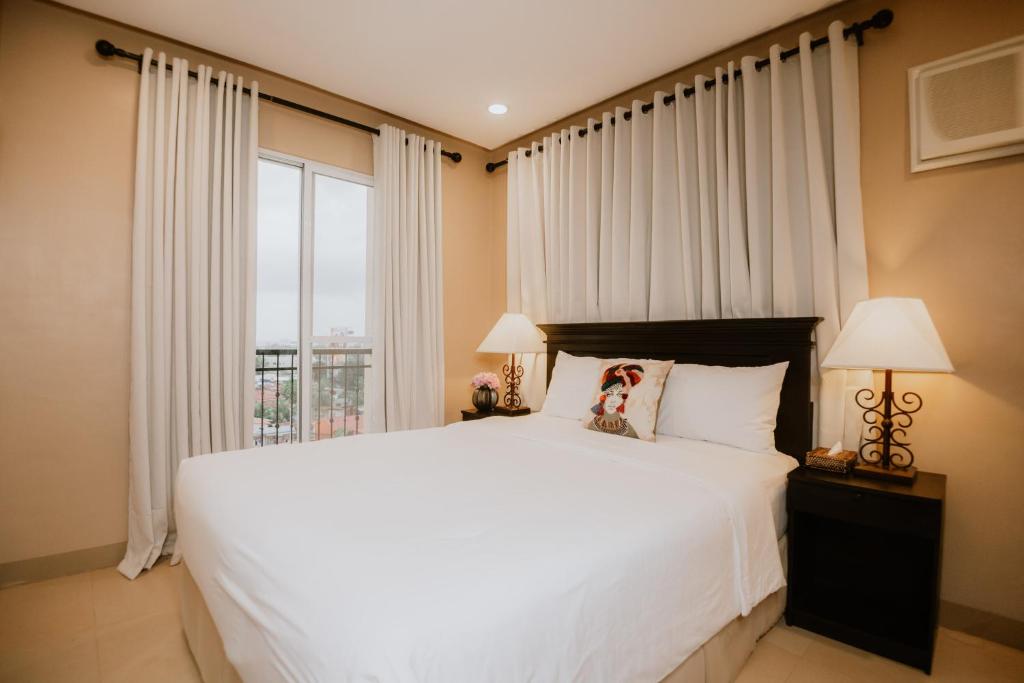 a bedroom with a large white bed and a window at Sta Barbara Residence Hotel in Cebu City