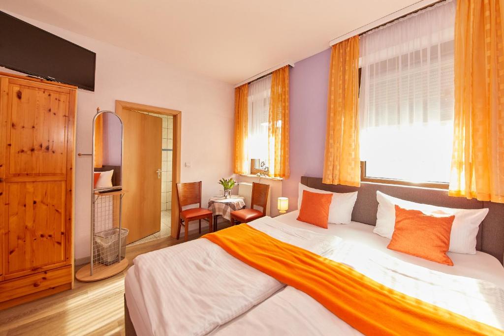 ein Schlafzimmer mit einem großen Bett mit orangefarbenen Kissen in der Unterkunft Hotel zum dicken Baum in Mayen