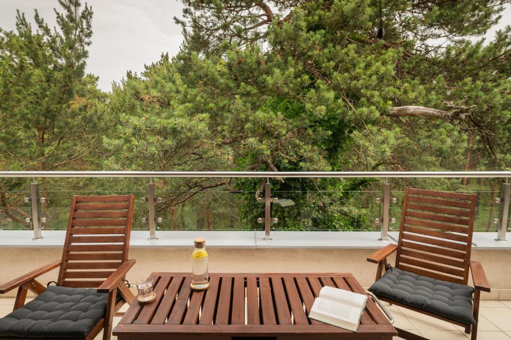 two chairs and a wooden table on a balcony at Apartamenty.in Jurata Ratibora 66 in Jurata