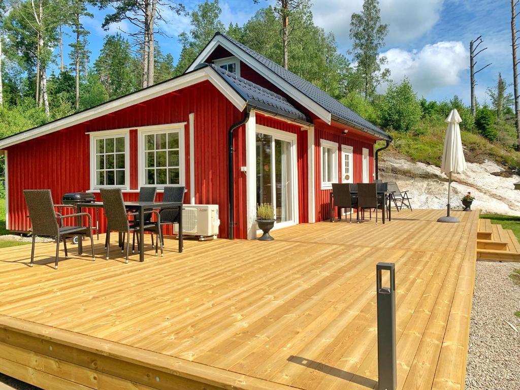 una terraza con cabina roja con mesa y sillas en The Buar Cabin en Strömstad