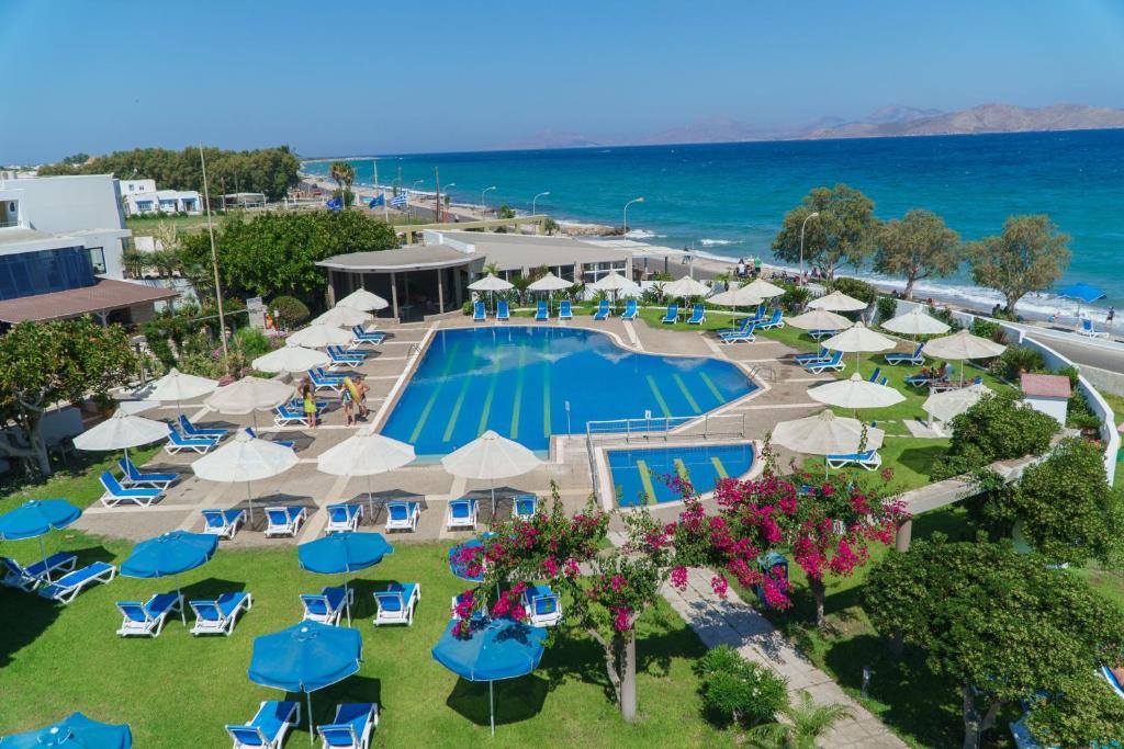 una vista aérea de un complejo con piscina, sillas y sombrillas en Kos Palace en Tigaki