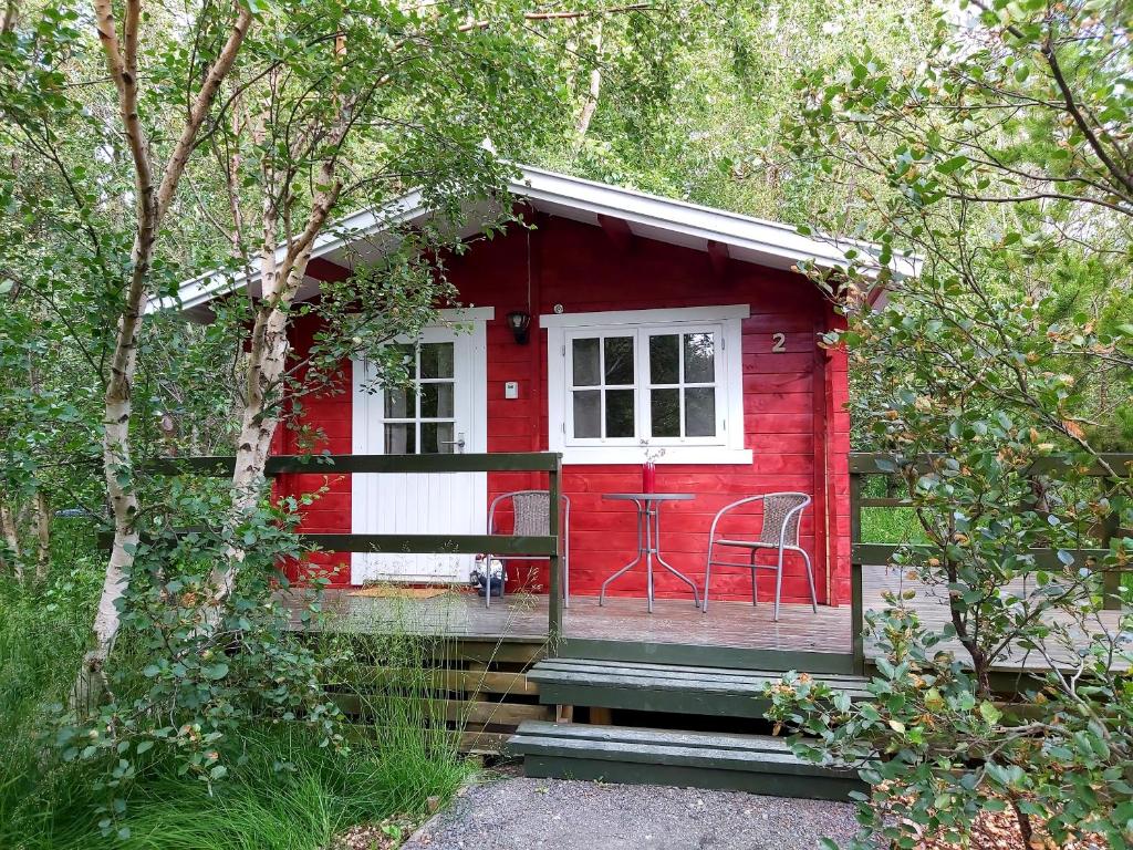 uma casa vermelha com uma janela branca e uma cadeira em Bakkakot 2 - Cozy Cabins in the Woods em Akureyri