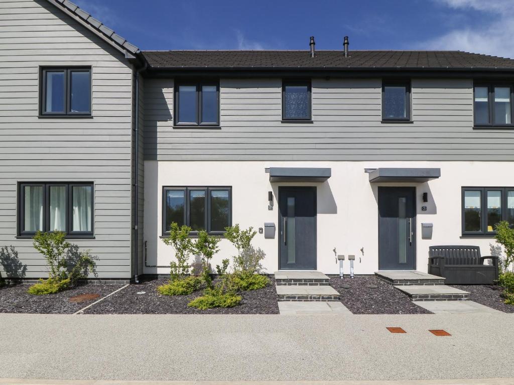 une maison blanche avec des fenêtres noires dans l'établissement Dune Retreat, à Rhosneigr