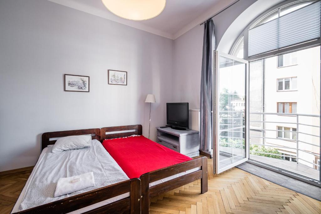 a bedroom with a bed and a tv and a large window at Apartamenty Lea 17 WAWELOFTS in Krakow