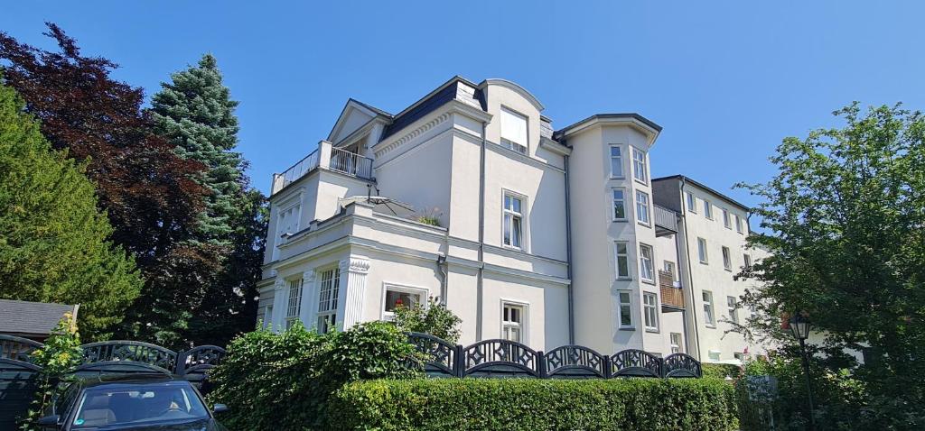 ein großes weißes Gebäude mit einem Zaun davor in der Unterkunft Ferienwohnung in Villa in Stralsund