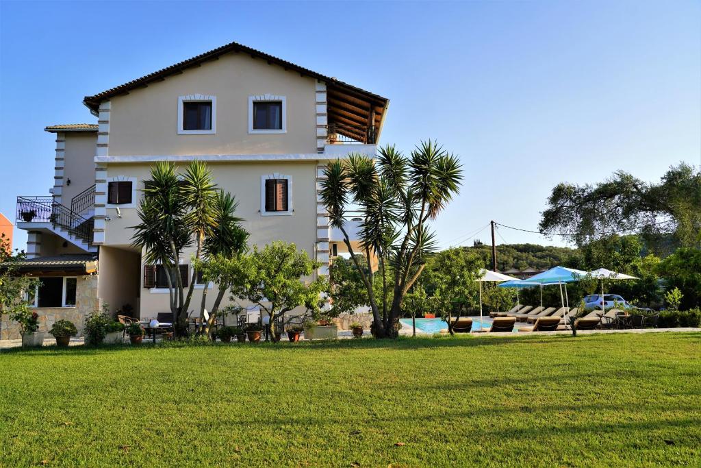 a white building with palm trees and a grass field at Villa Apollo in Parga