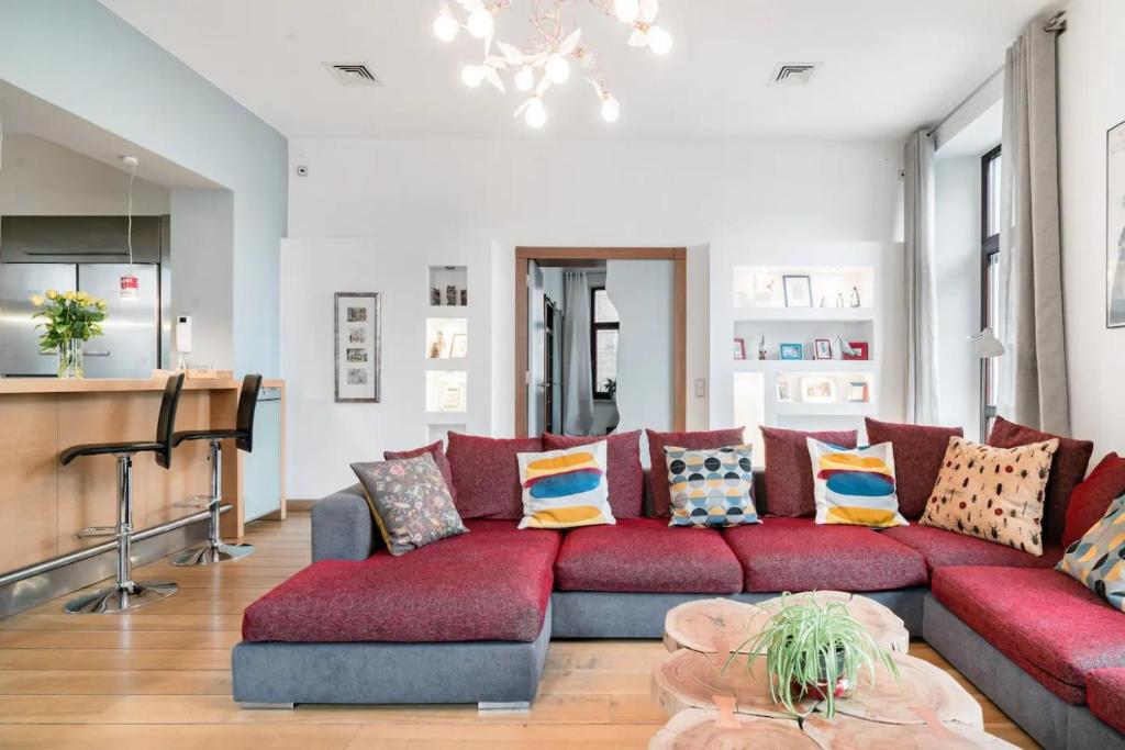 a living room with a red couch with pillows at Style4rent Apartament Kazimierz in Krak&oacute;w