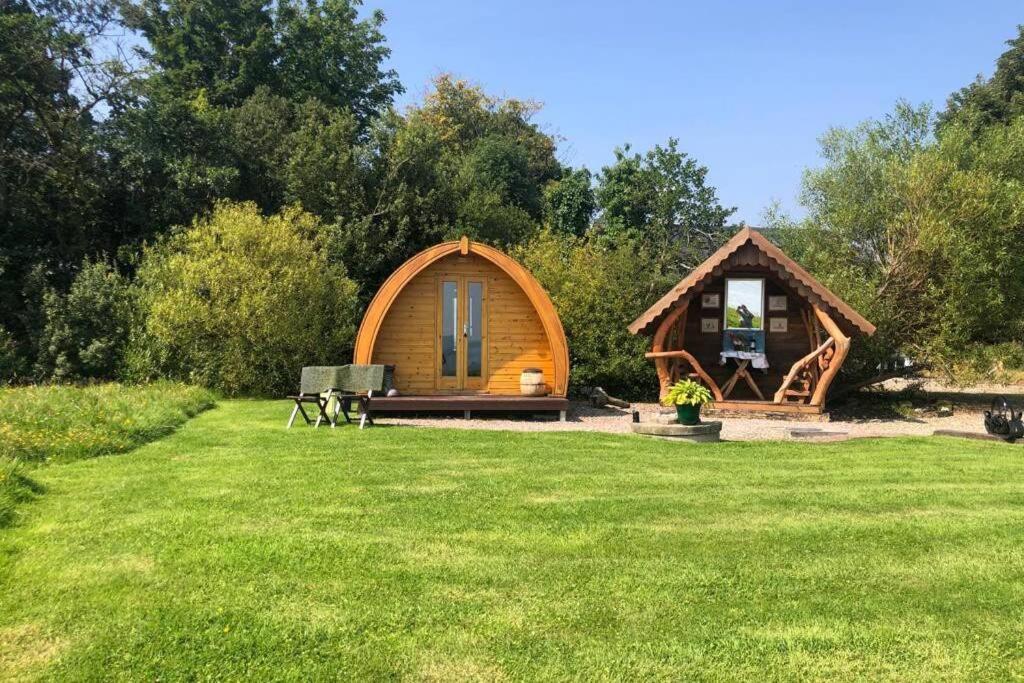 a small wooden cabin in a field of grass at River View Log Cabin Pod - 5 star Glamping Experience in Muff