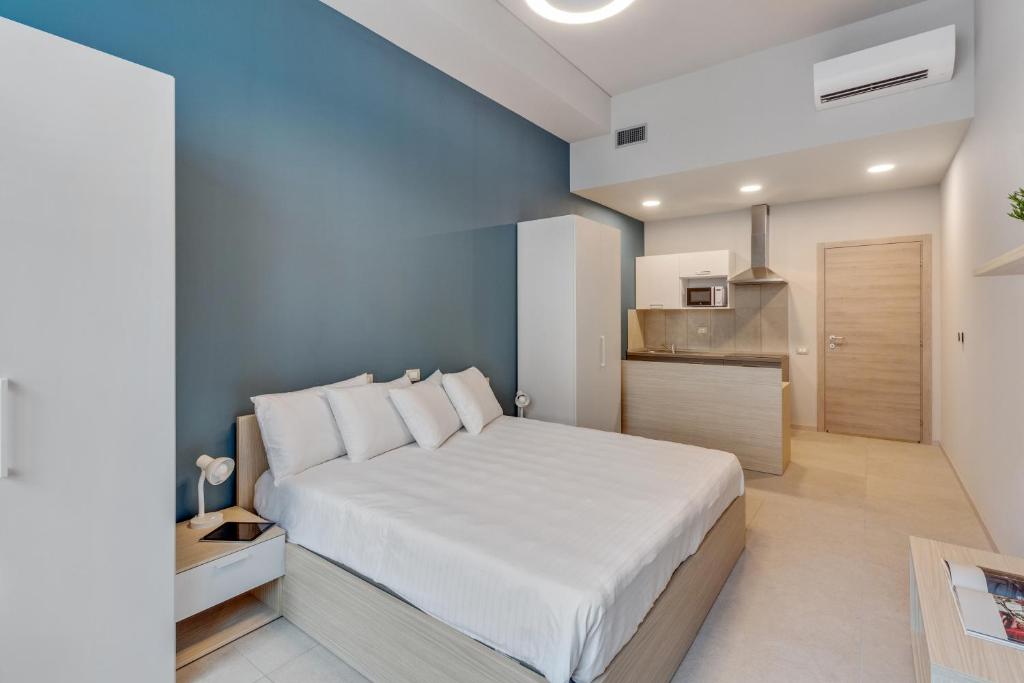Cet appartement comprend une chambre avec un grand lit blanc et une cuisine. dans l'établissement Camplus Regio Parco, à Turin