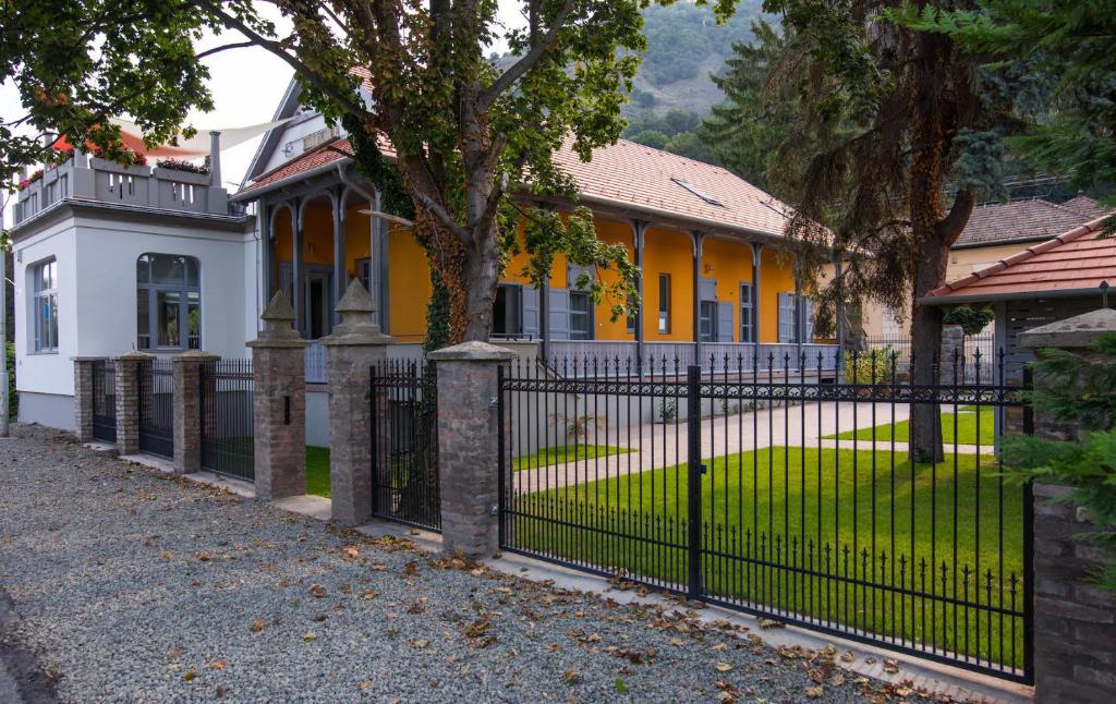 a black fence in front of a yellow house at Anna Vendégház in Visegrád