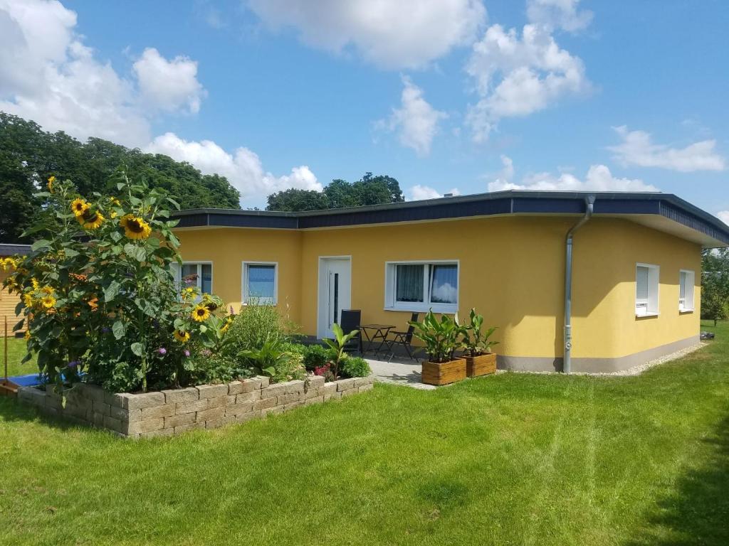 una piccola casa gialla con un giardino di fronte di Ferienhaus zum Imker a Velten