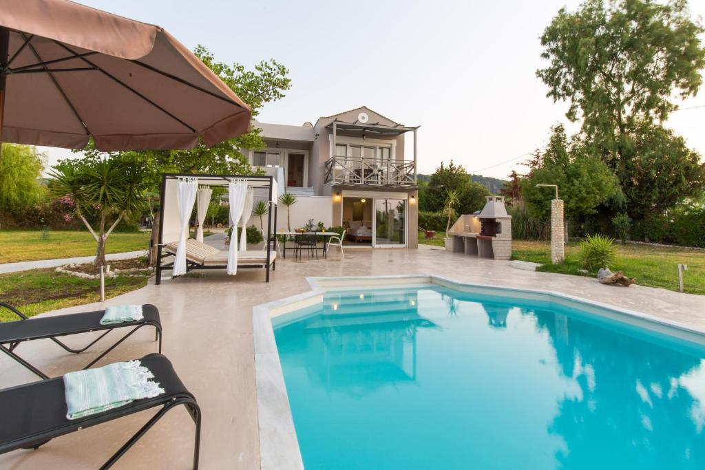 a swimming pool with an umbrella next to a house at Gyra Villas - Seaview Villa Fivos with private pool in Lefkada