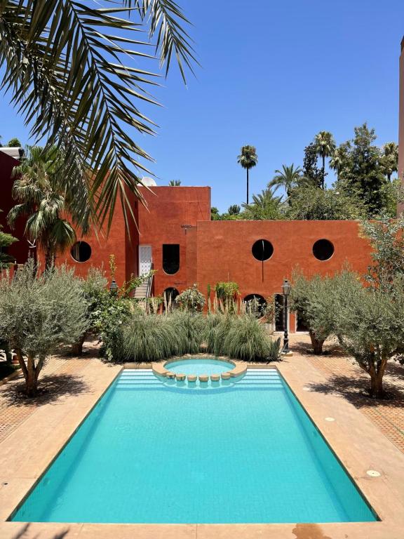 einem Pool vor einem Backsteingebäude in der Unterkunft MORO Marrakech Boutique Hôtel in Marrakesch