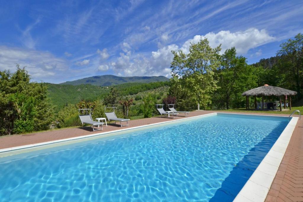 una piscina con sillas y vistas a las montañas en Villa Piombona, en Anghiari