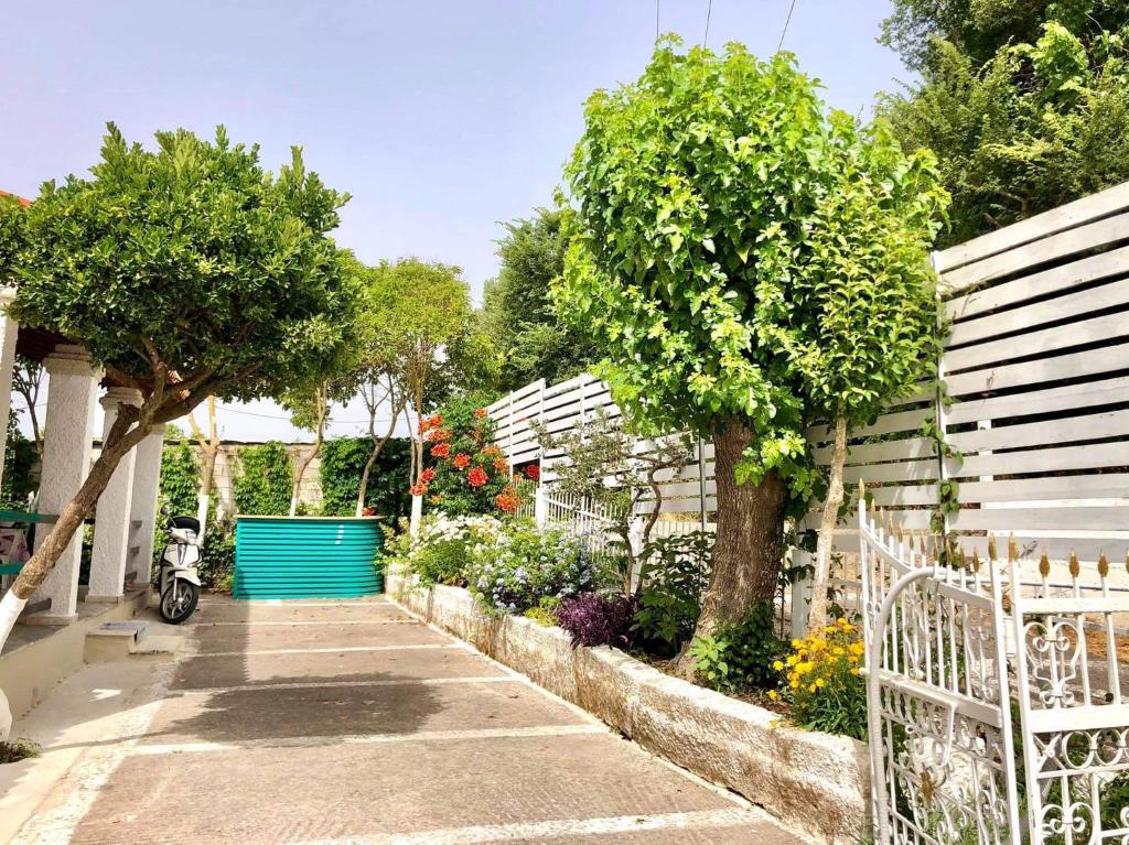 a garden with a white fence and trees and flowers at Villa Maria 1 in Liapades
