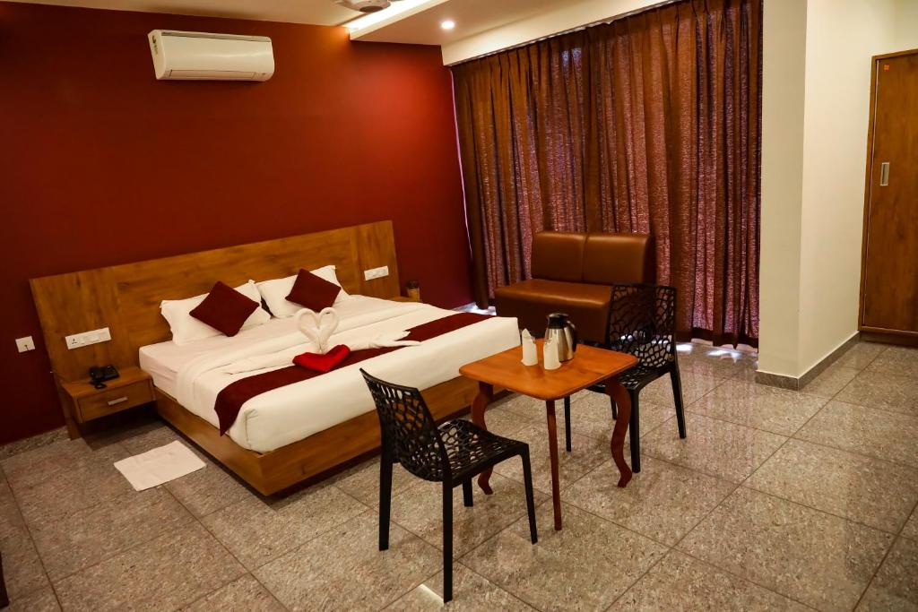 a bedroom with a bed and a table and chairs at Hillfort Inn in Sultan Bathery