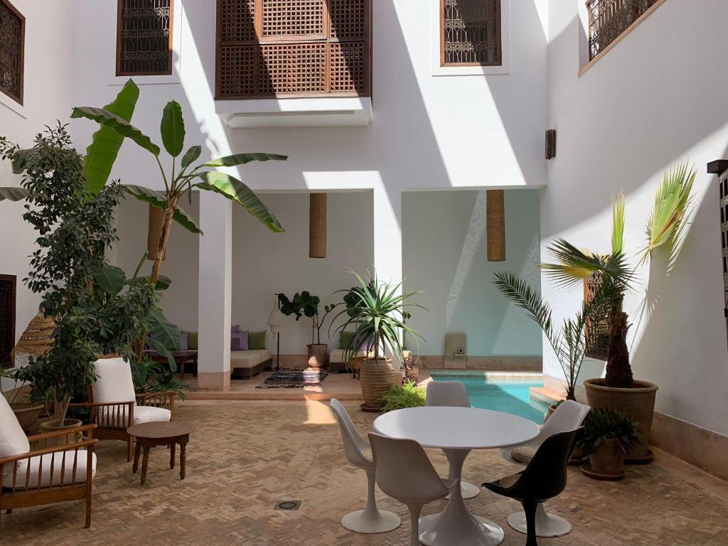 vestíbulo con mesa, sillas y piscina en Riad UP, en Marrakech