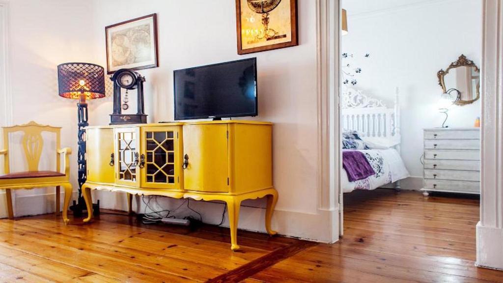 a living room with a television on a yellow cabinet at Find Me Inn Boutique Penthouse in Lisbon