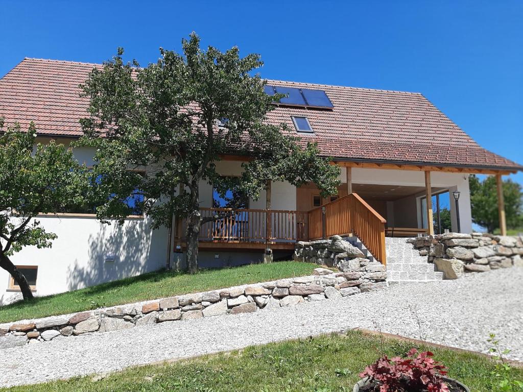 a house with a stone retaining wall and a deck at Rooms & Wine Lilek in Šentilj