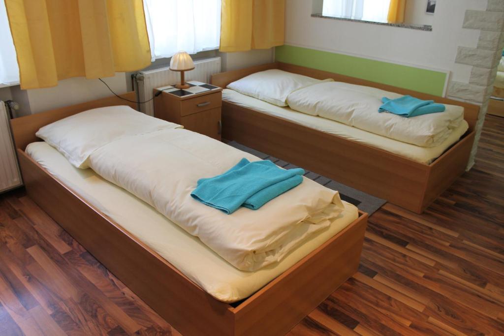 twee bedden in een kamer met twee blauwe kussens erop bij Pension Central Nuernberg-Fuerth in Fürth