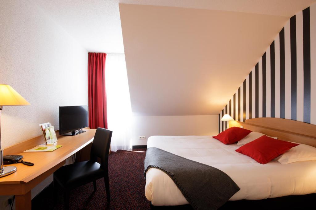 シャルトルにあるLogis Hôtel L'Orée de Chartres - Barjouvilleのベッドとデスクが備わるホテルルームです。