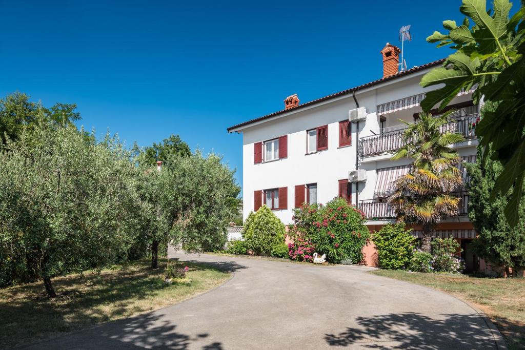 uma estrada em frente a um edifício com árvores em Apartments Marcan em Porec