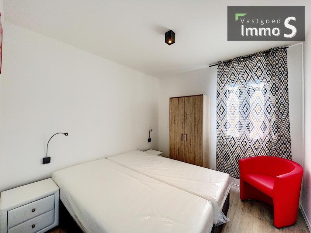 a bedroom with a bed and a red chair at New Dahlia in Bredene