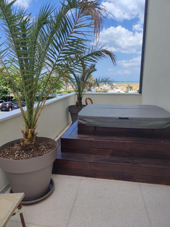 a bedroom with a bed and palm trees on a balcony at Hotel Ambassador in Rimini