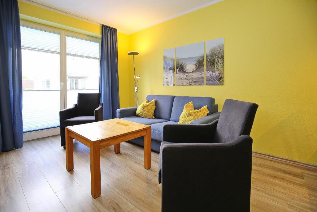 a living room with a blue couch and two chairs at Dünenblick Wohnung 42 in Boltenhagen