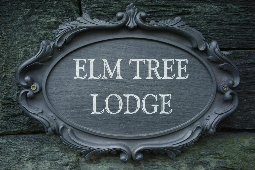 una señal que lee la cabaña de olmo en una pared en Elm Tree Lodge, en Keswick